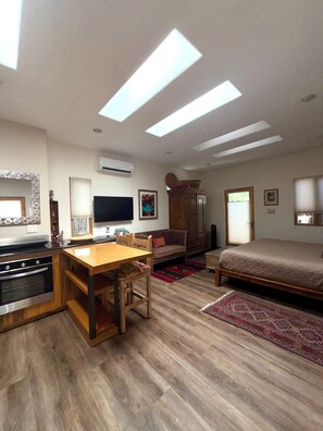 Un soggiorno moderno con un tavolo da pranzo in legno, un divano, una TV e un letto grande.