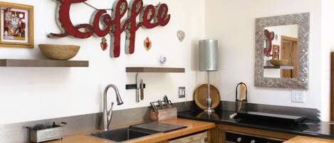 Una cocina con encimera de madera, un lavabo y un adorno mural con temática de café.