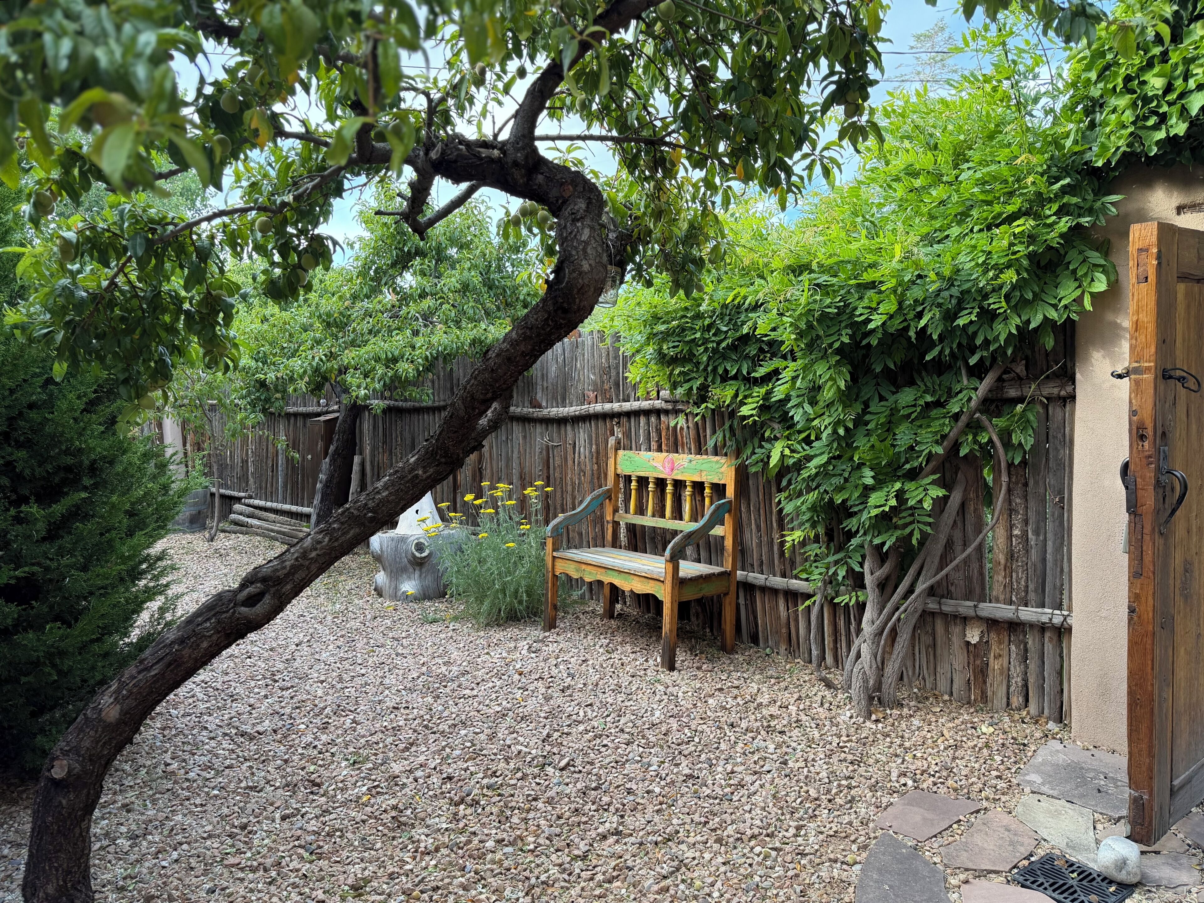 Un espacio al aire libre rústico con un banco de madera, una valla de madera y un camino de piedra.
