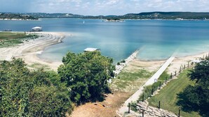 Paesaggio costiero con vista aperta sul mare, una spiaggia sabbiosa e un sentiero che conduce a un edificio bianco.