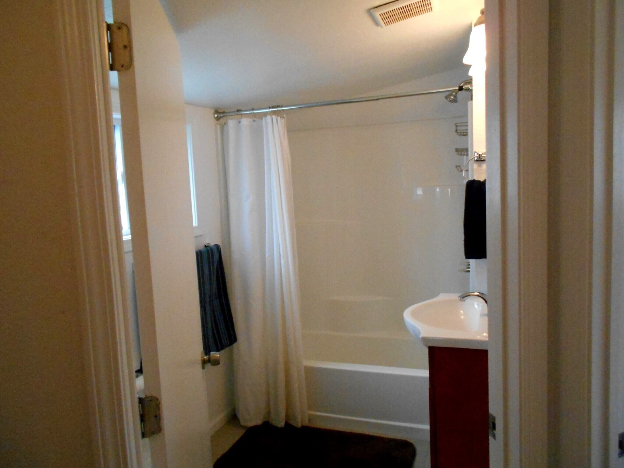 Une salle de bain avec une baignoire, un lavabo blanc et un rideau de douche.