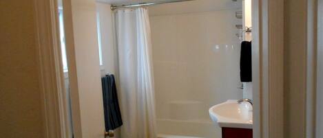 Une salle de bain avec une baignoire, un lavabo blanc et un rideau de douche.