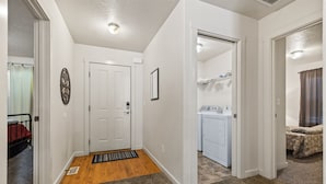 A hallway with a door, a doormat, and a laundry area with a washing machine. - Fenced Yard | Updated Kitchen | Quiet Neighborhood (Meridian)