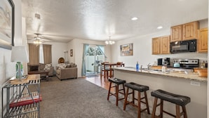 A compact kitchen with wooden cabinets, a microwave, and a dining area with stools. - Fenced Yard | Updated Kitchen | Quiet Neighborhood (Meridian)