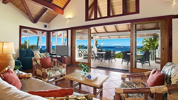 Ein großzügiger Wohnbereich mit großem Fernseher, bequemen Sitzgelegenheiten und Blick aufs Meer.