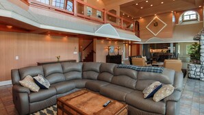 A spacious living area with a large sectional sofa, a wooden coffee table, and a staircase leading to an upper level. - Walk to Drakes Island Beach, Large Kitchen & Yard, Theater & Gym! Very Private (Wells)
