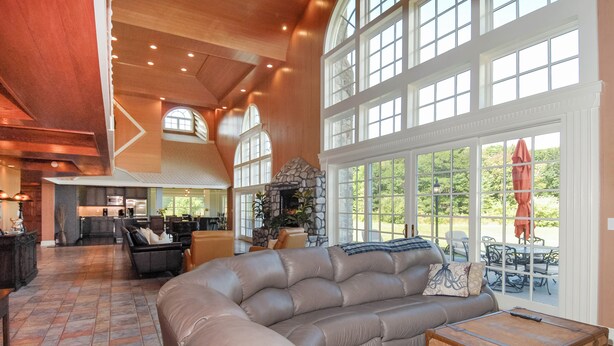 A spacious living area with a large sectional sofa, a stone fireplace, and a view through large windows. - Walk to Drakes Island Beach, Large Kitchen & Yard, Theater & Gym! Very Private (Wells)