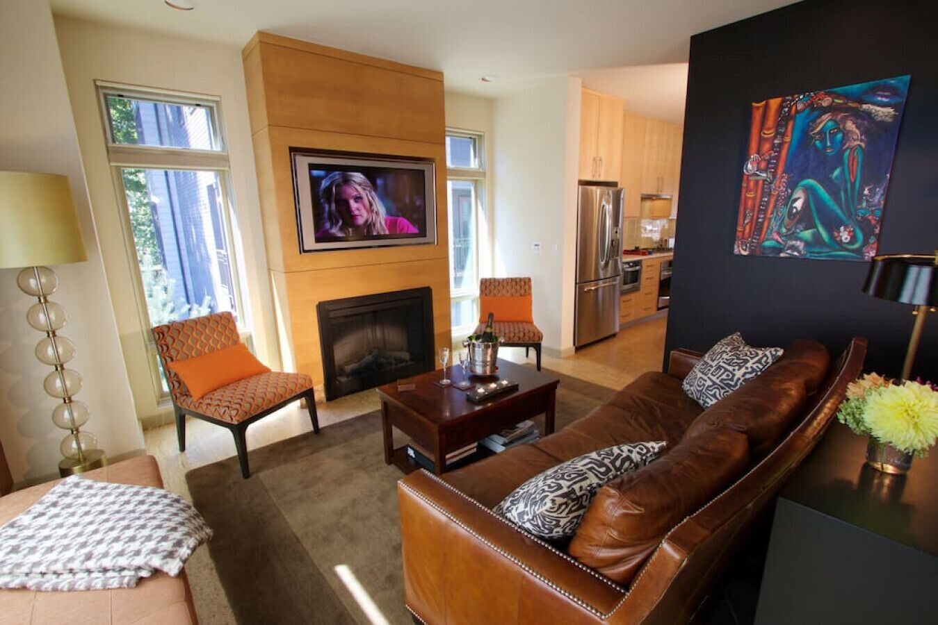 Una sala de estar moderna con chimenea, un sofá de cuero y un televisor montado en la pared.