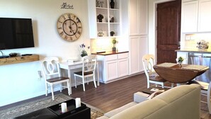 A living room with a TV, a clock, a dining table, and chairs. - VIEWS! Texas Hill Country - Terra Vista (Dripping Springs)
