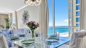 Comedor con mesa de vidrio, sillas y vista a la playa.