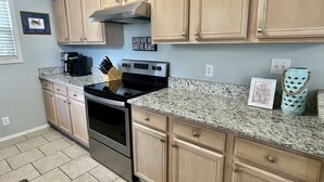 A kitchen with light wood cabinets, a stainless steel stove, granite countertops, and a coffee maker. - Sandy Feet Retreat-1/2 Block to Beach, Pet Friendly, Wi-Fi & Optional GC Rental  (Surfside Beach)