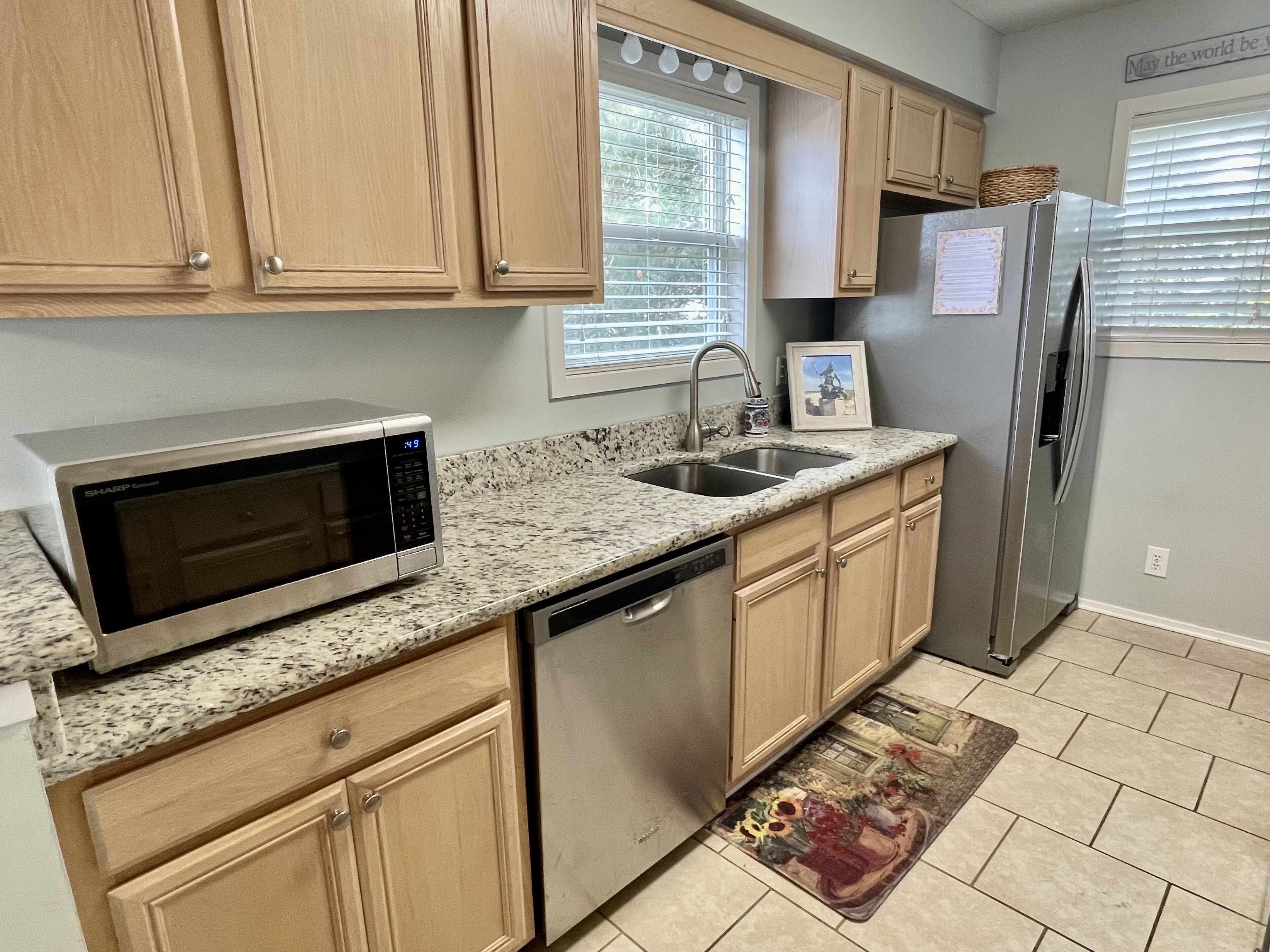 A kitchen with wooden cabinets, a stainless steel refrigerator, a microwave, and a dishwasher.
