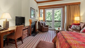 A hotel room with a desk, television, fireplace, seating area, and a balcony with a view of trees. - Luxury Studio Ski in -ski out Mt Mansfield Views, Mountain Golf Course Access (Stowe)