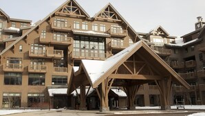A multi-story building with a ski lodge entrance, wooden balconies, and a snow-covered roof. - Luxury Studio Ski in -ski out Mt Mansfield Views, Mountain Golf Course Access (Stowe)