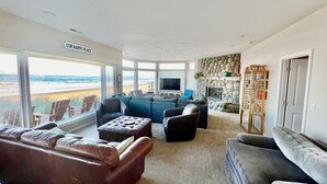 A spacious living room with a large TV, comfortable seating, and a stone wall.