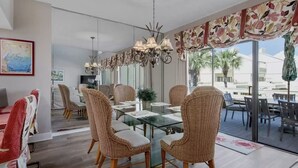 Et moderne spiseområde med fletstole, et glasbord og udsigt til palmer udefra.
