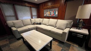 Un salon moderne avec un canapé d’angle, une table basse et un tableau accroché au mur.