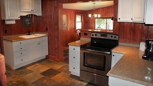 Une cuisine avec un lambris en bois, des armoires blanches, une cuisinière en acier inoxydable et un comptoir en granit.