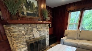 Un salon avec une cheminée en pierre, un canapé beige et une table basse en marbre.