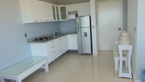 A modern kitchen with white cabinets, a stainless steel refrigerator, and a granite countertop.