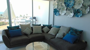 A modern living room with a sectional sofa, a glass coffee table, and decorative wall art.