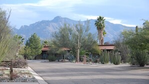 A desert landscape with a road, cacti, and a building with a red roof. - Wonderful Whispering Hills (Tucson)