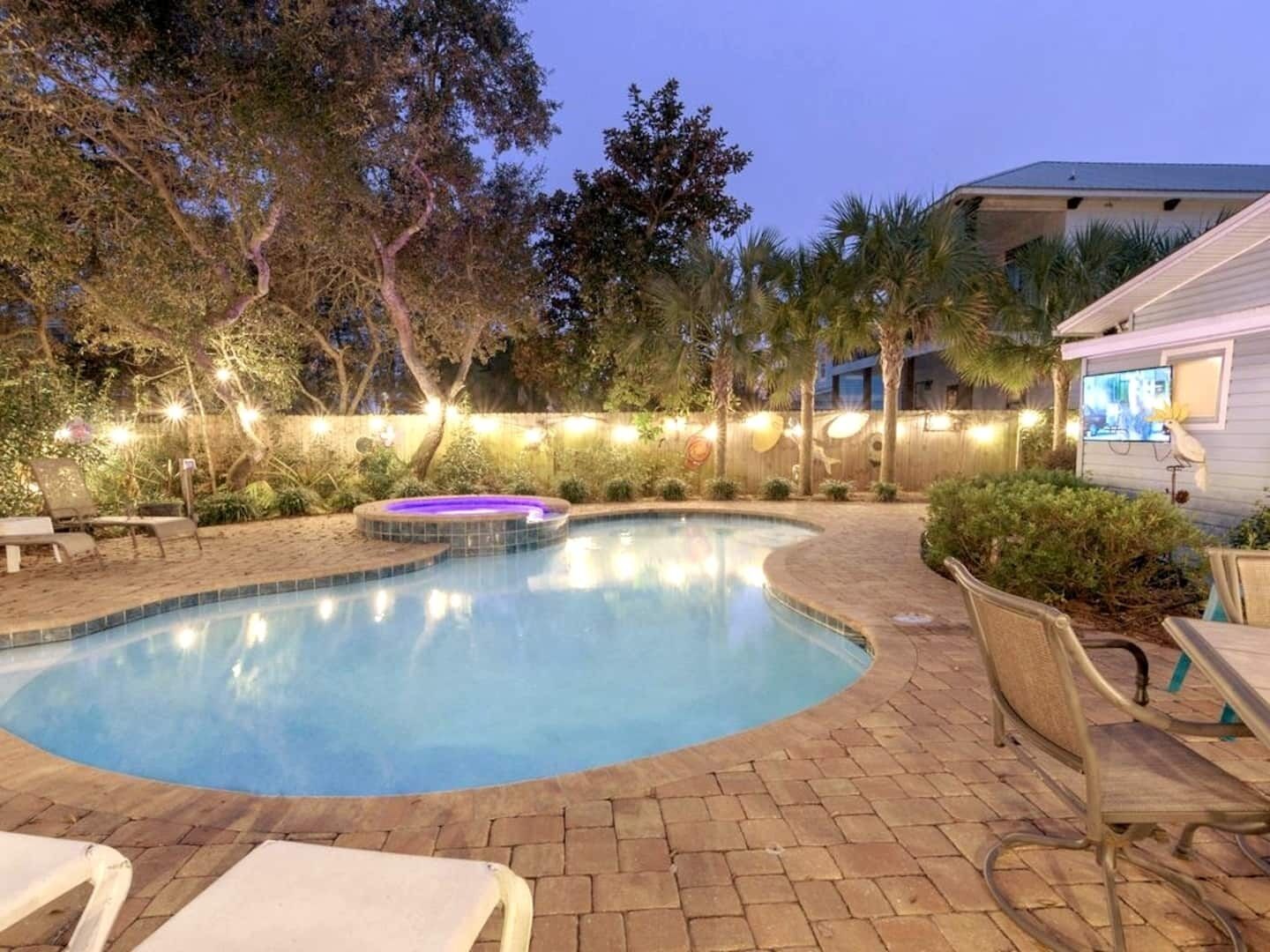 Piscina com hidromassagem, rodeada por espreguiçadeiras e um deck de madeira.
