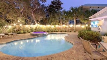 Piscina com hidromassagem, rodeada por espreguiçadeiras e um deck de madeira.