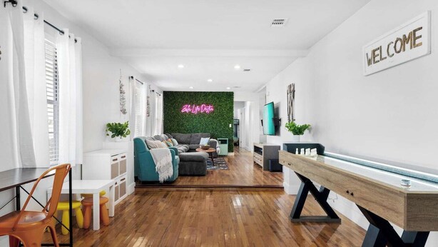 Een moderne woonkamer met houten vloer, een zithoek, een salontafel en een televisie.