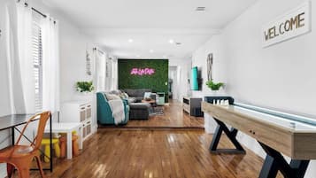 Uma sala de estar moderna com piso de madeira, um sofá, uma mesa de centro e uma televisão.