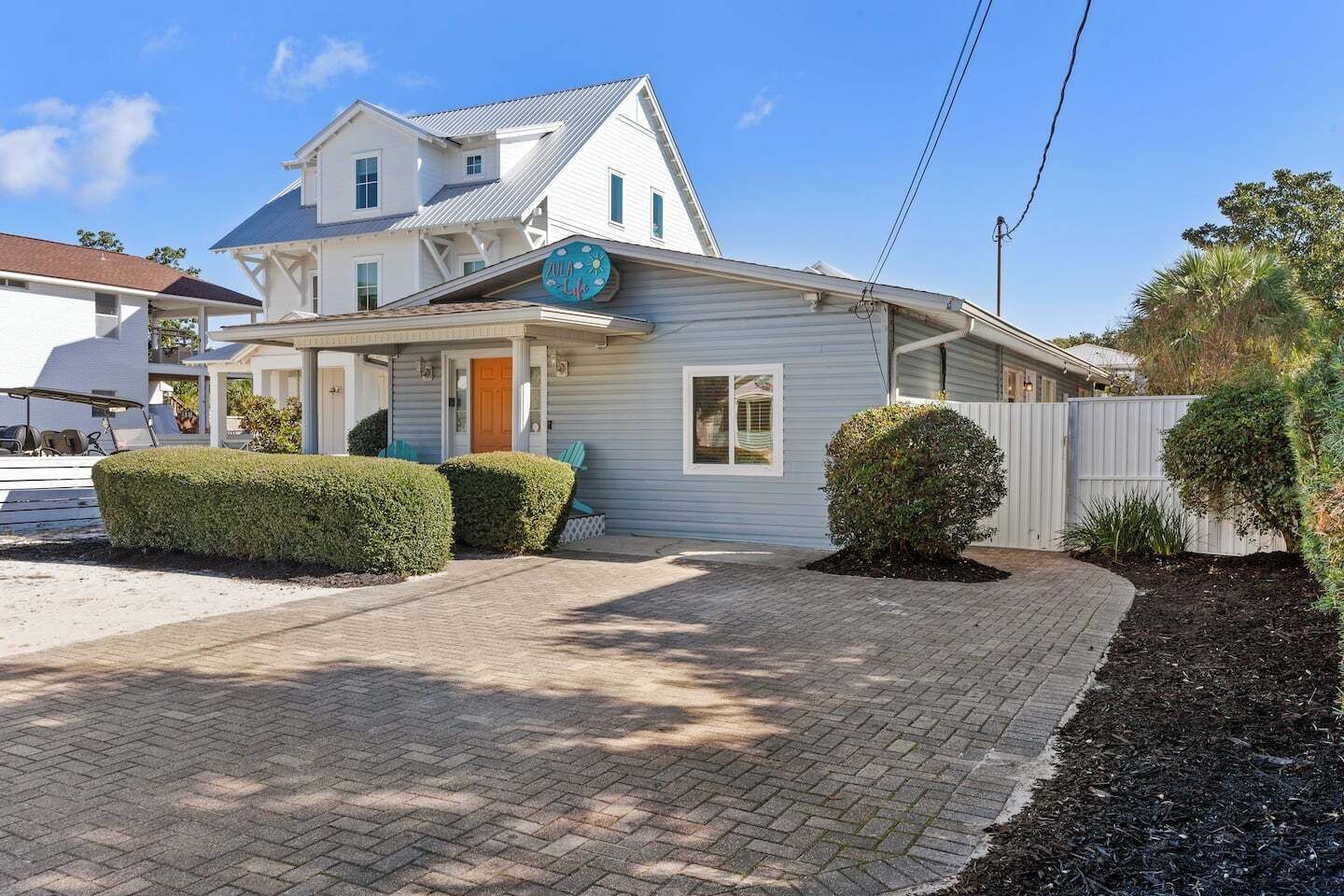 A two-story house with a covered porch, a garage, and a well-maintained front yard with hedges and a brick driveway.