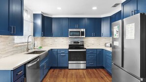 Een moderne keuken met blauwe kastjes, roestvrijstalen apparatuur en een houten vloer.