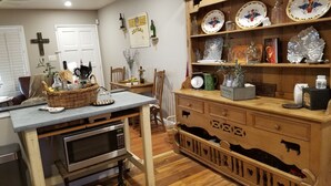 Een keuken met een houten tafel, een magnetron en een mand met spullen.