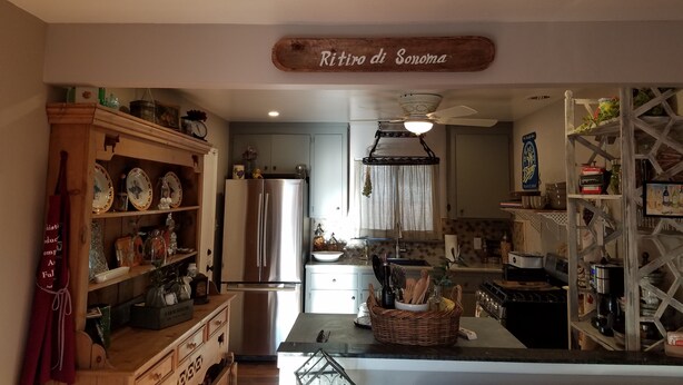 Een keuken met een houten bord boven de deur, een koelkast en een centraal eiland met een mand.