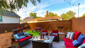 Ein Hinterhof mit Terrassenausstattung, einem Grill und einem Holzzaun.