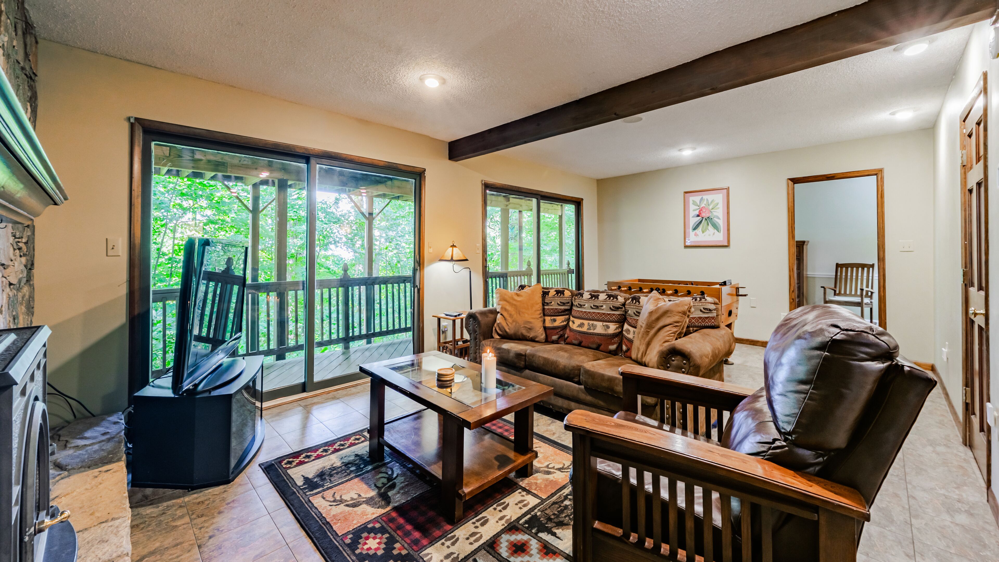 A spacious living room with a large window, a fireplace, a sofa, a coffee table, and a leather chair.