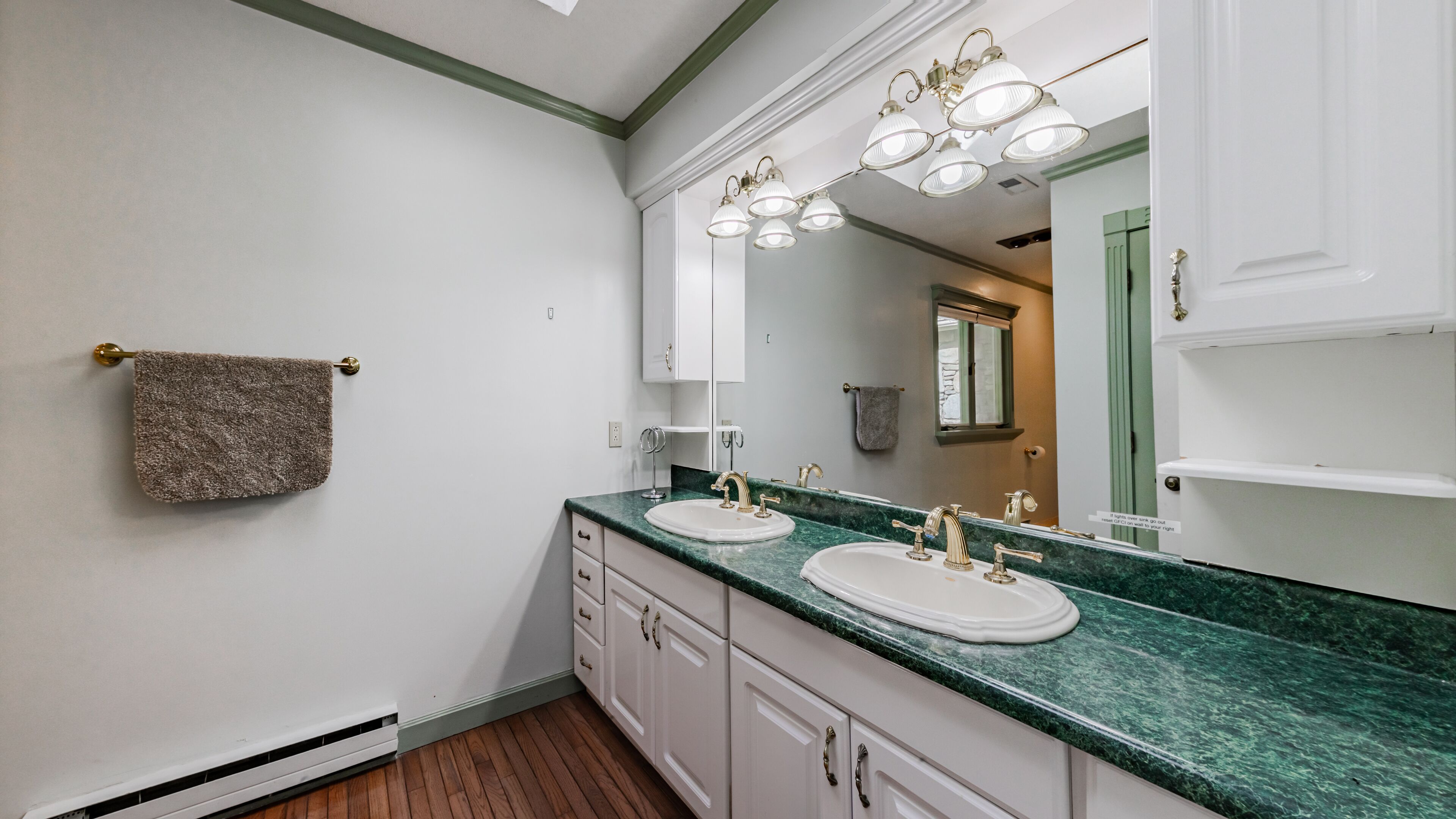 A bathroom with two sinks, a towel rack, and a mirror with lights.
