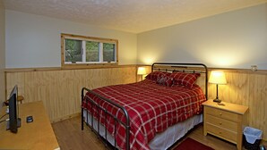 Une chambre à coucher avec un lit, des tables de chevet, une fenêtre et un bureau avec un ordinateur.
