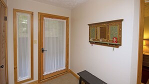 Une pièce avec deux portes, un banc et un miroir au mur.