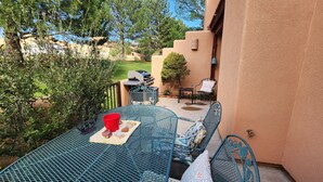 A patio with a metal table and chairs, a grill, and a small garden area. - Family and Pet Friendly Condominium in Moab by Golf Course  (Moab)