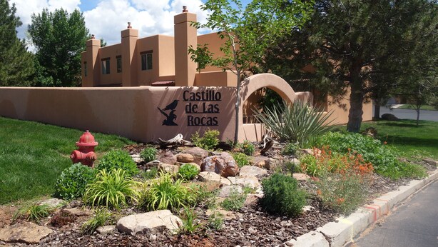 A building with a sign reading "Castillo de las Rocas" and a landscaped garden with rocks and plants. - Family and Pet Friendly Condominium in Moab by Golf Course  (Moab)