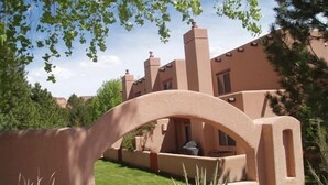 A stucco building with a large arched entrance, a patio area, and a well-maintained lawn. - Family and Pet Friendly Condominium in Moab by Golf Course  (Moab)