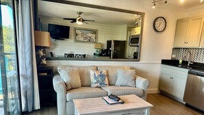 A living room with a striped sofa, a coffee table, and a TV. - SeaGem-Oceanview! Steps to ocean Many Upgrades New Reno (Hilton Head Island)