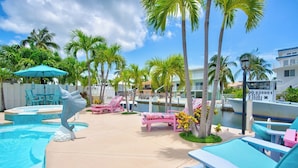 A pool area with lounge chairs, a decorative fish sculpture, and a boat dock. - P11 - Charming 2 bedroom 2 bath duplex with private pool and dock - Completely updated. (Marathon)