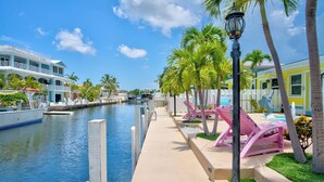 A waterfront hotel with a canal, lounge chairs, and palm trees. - P11 - Charming 2 bedroom 2 bath duplex with private pool and dock - Completely updated. (Marathon)