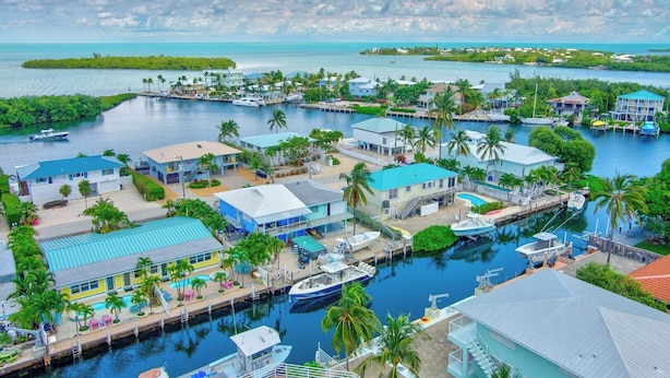 A coastal marina with multiple boats docked, surrounded by residential buildings and lush greenery. - P11 - Charming 2 bedroom 2 bath duplex with private pool and dock - Completely updated. (Marathon)