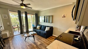 A living room with a sofa, coffee table, and a ceiling fan. There is a sliding glass door leading to a balcony. - Salty Shores! -Incredible ocean views (Hilton Head Island)