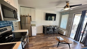 A compact kitchen with a refrigerator, microwave, and stove. There is a dining area with a table and chairs, and a ceiling fan above. - Salty Shores! -Incredible ocean views (Hilton Head Island)