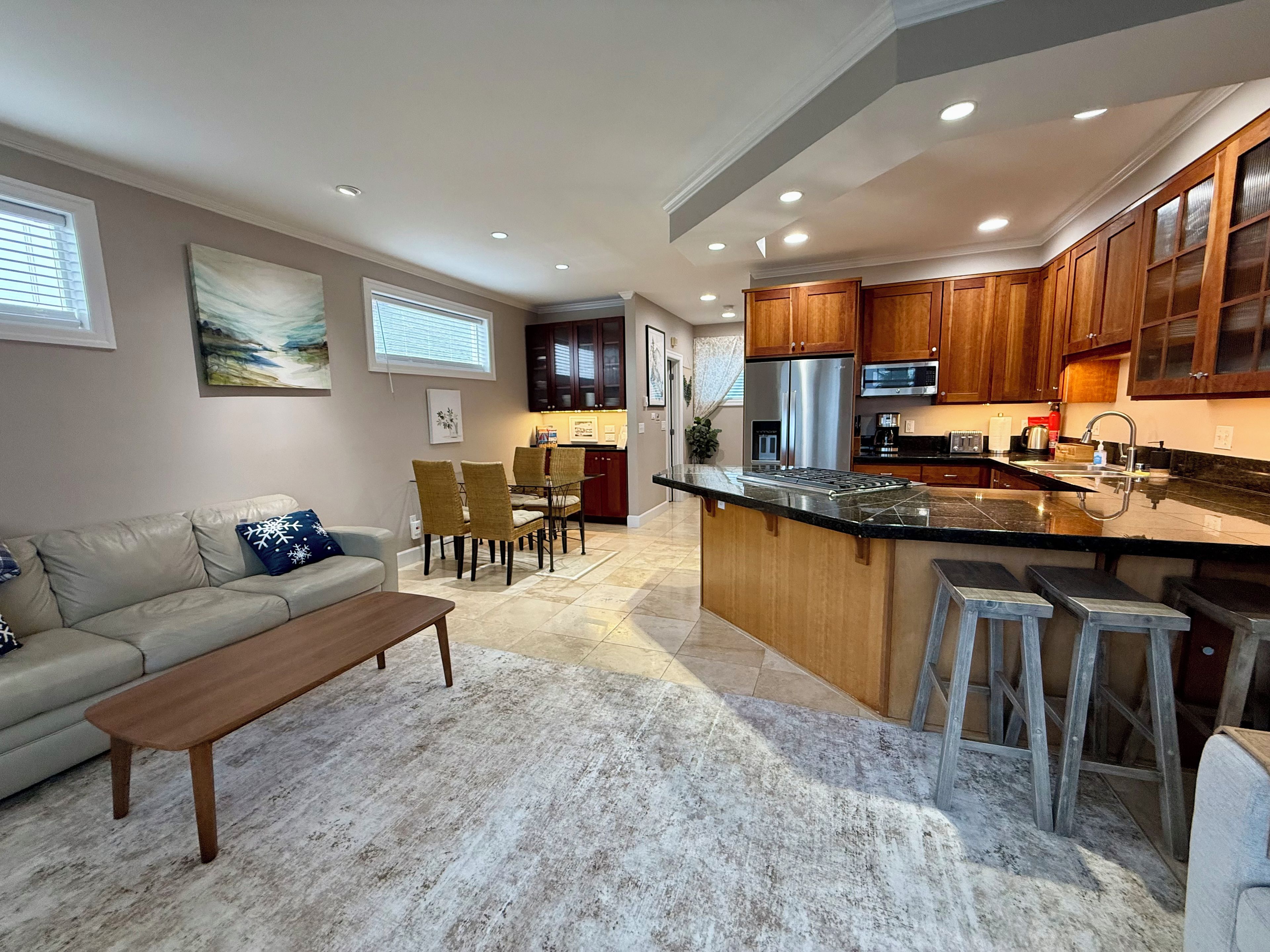A modern kitchen with wooden cabinets, stainless steel appliances, and a marble countertop.