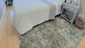 A bedroom with a large bed, a bedside table with a lamp, a wall-mounted TV, and a window with blinds. - 180° Space Needle, Lake Union & Downtown Views! (Seattle)